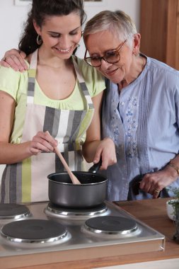 Granddaughter cooking for her grandmother clipart