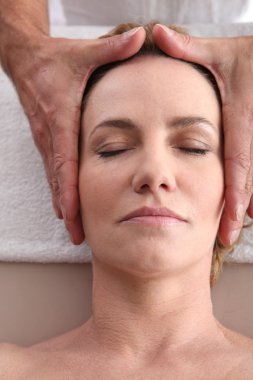 Woman being given a head massage. clipart