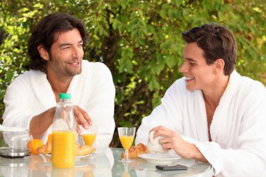 Two male housemates having breakfast outdoors clipart