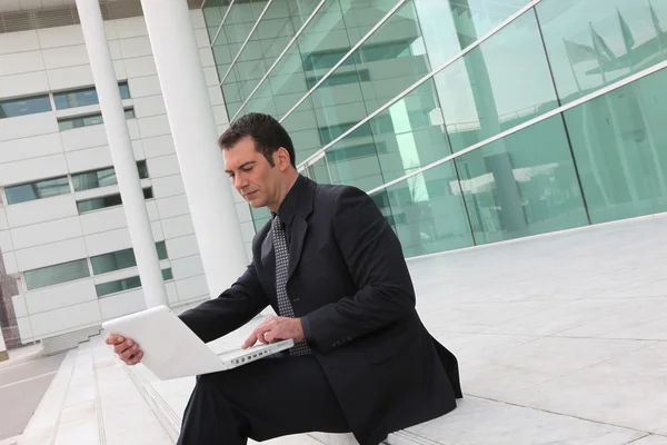 Бизнесмен, сидящий на лестнице с компьютером — стоковое фото