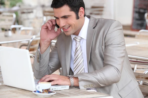 Homme utilisant un ordinateur portable et un téléphone portable dans un café — Photo