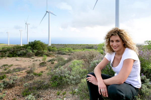 Jovem mulher sentada perto de turbinas eólicas — Fotografia de Stock