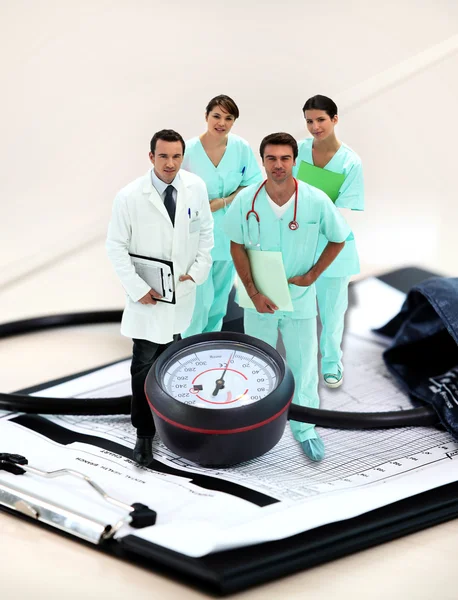Portrait of medical staff amid giant clipboard and sphygmomanometer — Stock Photo, Image