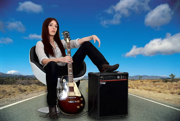 Gestileerde vrouwelijke gitarist met haar versterker op de weg — Stockfoto