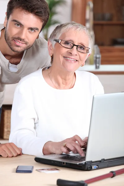 Молодий чоловік допомагає старшій жінці з портативним комп'ютером — стокове фото
