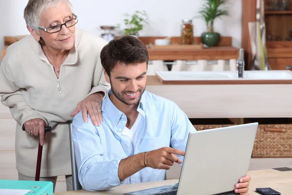 Мужчина показывает старушке, как пользоваться компьютером — стоковое фото