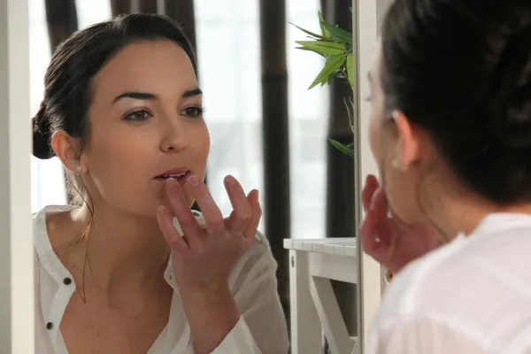 Γυναίκα που εφαρμόζουν lip gloss σε έναν καθρέφτη — Φωτογραφία Αρχείου