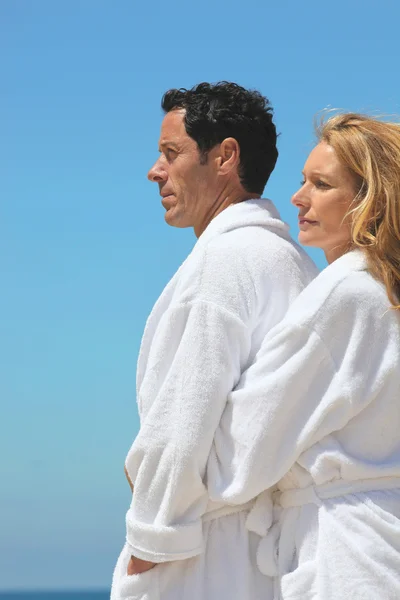 Perfil vista de casal pelo mar vestindo roupões de banho — Fotografia de Stock