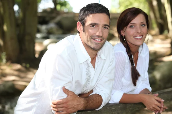 Par i vitt lutad mot ett staket i trä — Stockfoto
