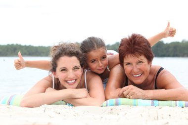 Three generations - grandmother, mother and daughter - on the beach clipart