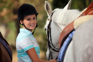 Young woman taking care of her horse clipart