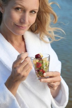 Woman eating a glass of fruit salad clipart