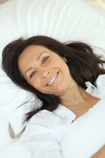 Χαμογελαστή γυναίκα ξαπλωμένη στο κρεβάτι — Φωτογραφία Αρχείου