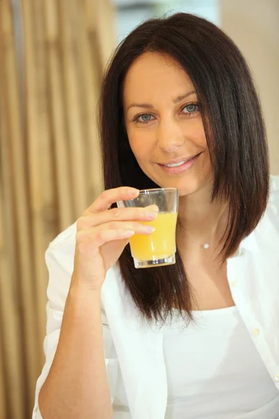 Μελαχρινή γυναίκα πίνοντας χυμό πορτοκαλιού — Φωτογραφία Αρχείου