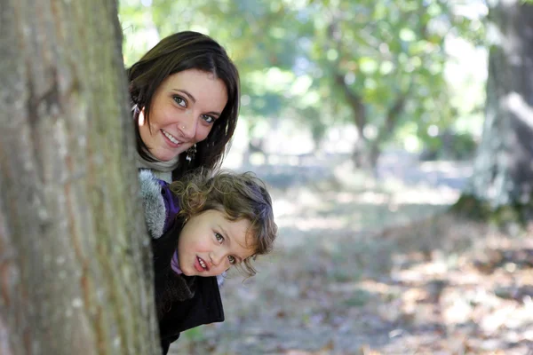 Mamma och dotter gömmer sig bakom ett träd — Stockfoto