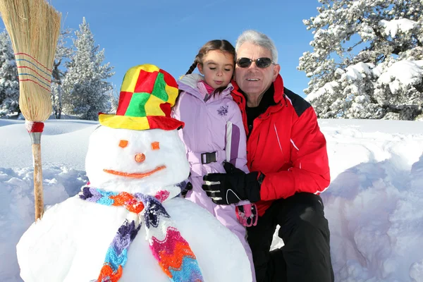 Far och dotter bygga snögubbe tillsammans — Stockfoto