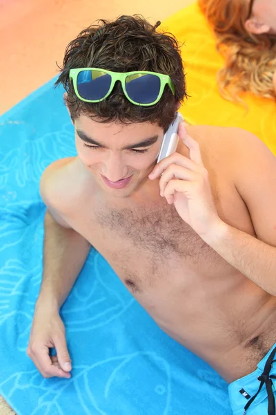 Mladý muž pomocí mobil na pláži — Stock fotografie
