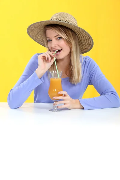 Женщина пьет апельсиновый сок через соломинку — стоковое фото