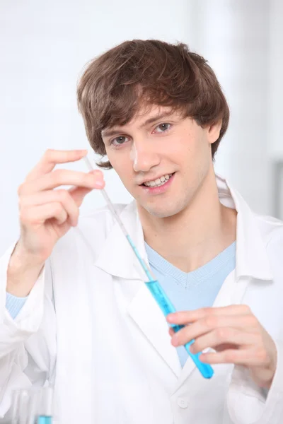 Ein junger Mann extrahiert eine Flüssigkeitsprobe aus einem Reagenzglas. — Stockfoto