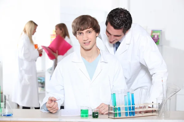 Teacher checking students work in laboratory — Stock Photo, Image