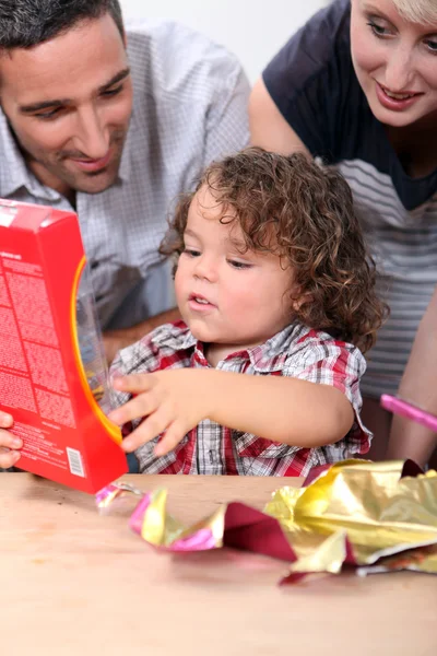 A szülők figyel a gyermek egy ajándék nyissa meg — Stock Fotó