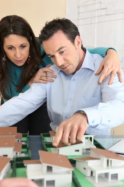 Arkitekt och assistent samlades runt modell bostäder — Stockfoto