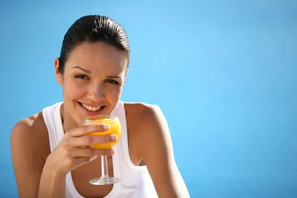 Morena bebiendo zumo de fruta en la piscina — Foto de Stock