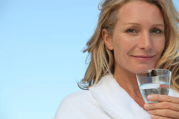 Attractive blonde haired woman with no make up on and drinking a glass of w — Stock Photo, Image