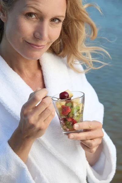 Vrouw eten een glas fruitsalade — Stockfoto