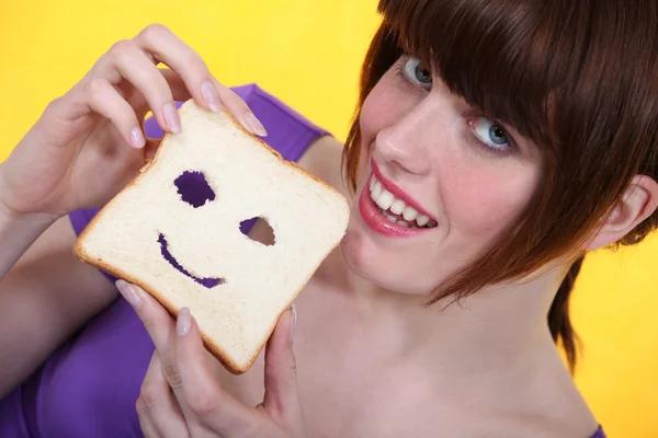 若い女性が彼女のパンのスライスで、顔を作る — ストック写真