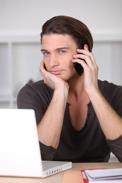 Schöner blauäugiger junger Mann telefoniert mit Computer — Stockfoto