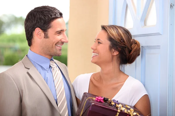 Muž dává dárek manželce poblíž dveře domu — Stock fotografie