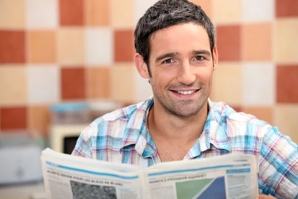 Чоловік читає газету на кухні — стокове фото
