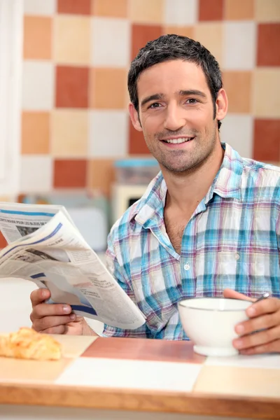 Homme lisant le journal tout en prenant le petit déjeuner — Photo
