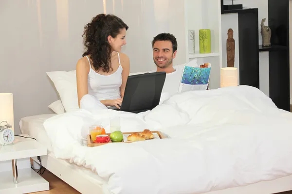 カップルはベッドで朝食を持っているノート パソコン — ストック写真