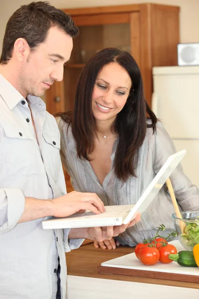 Para przy pomocy pewien laptop w kuchni — Zdjęcie stockowe
