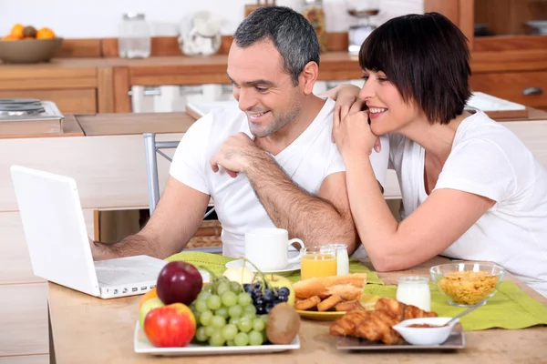Couple looking at a laptop during breakfast — Stock Photo, Image