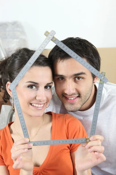 Couple tenant dispositif de mesure en forme de maison — Photo