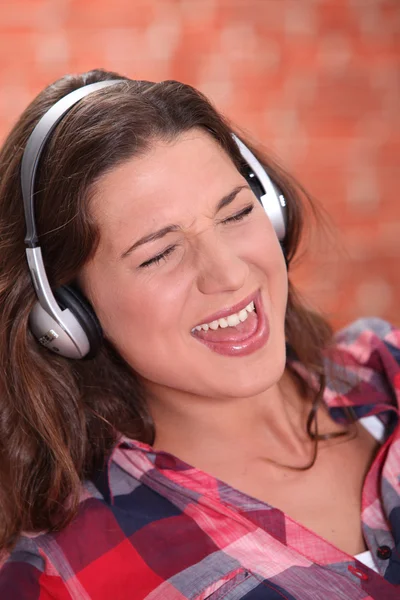 Morena usando fones de ouvido e cantando — Fotografia de Stock