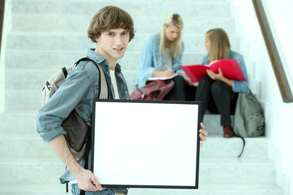 Студент коледжу, який тримає чорну рамку, ліворуч порожній для вашого зображення — стокове фото