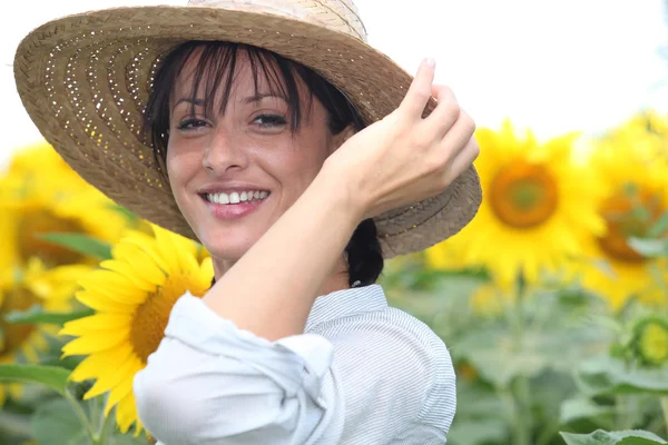Жінка в солом'яному капелюсі на соняшниковому полі — стокове фото