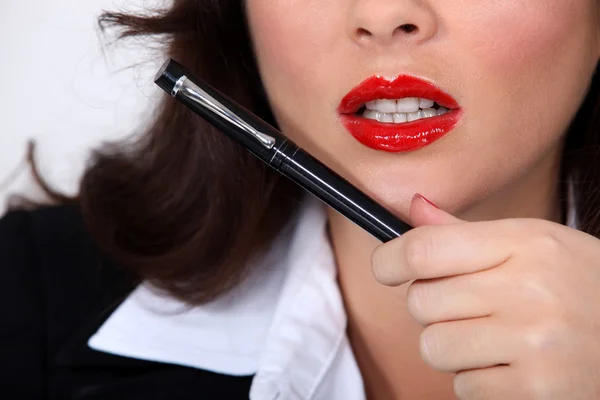 Närbild av en affärskvinna med rött läppstift hålla en penna — Stockfoto