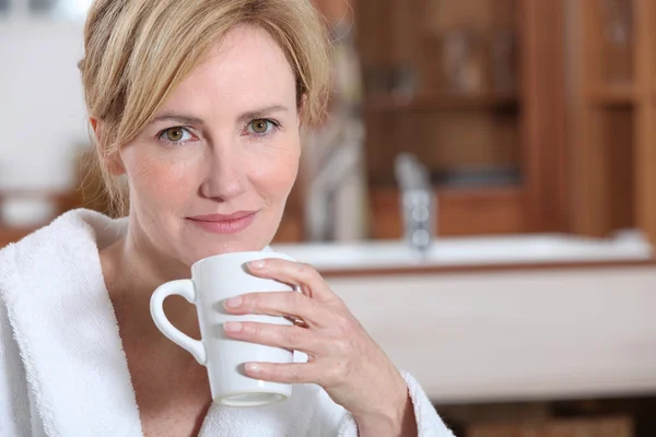 Blonde Frau im Morgenmantel trinkt Kaffee — Stockfoto