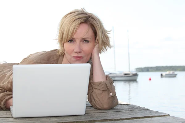 Woman on laptop by the lake — Stock Photo, Image