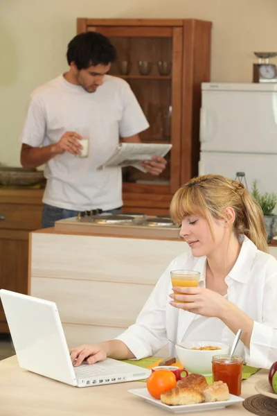 A woman having breakfast, her husband is reading newspaper Stock Photo