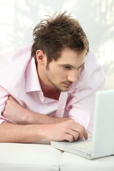 Man using his laptop on a sofa Stock Image