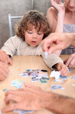 Little boy playing with pictures at a table clipart