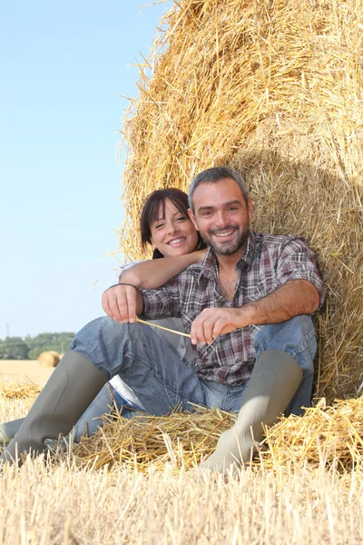 Farmář a žena seděla na balíku sena — Stock fotografie