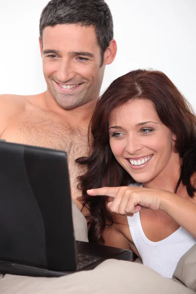 Een paar lachen achter een computer — Stockfoto