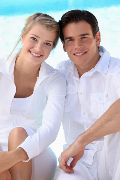 Young couple wearing white with a blue sky background — Stock Photo, Image